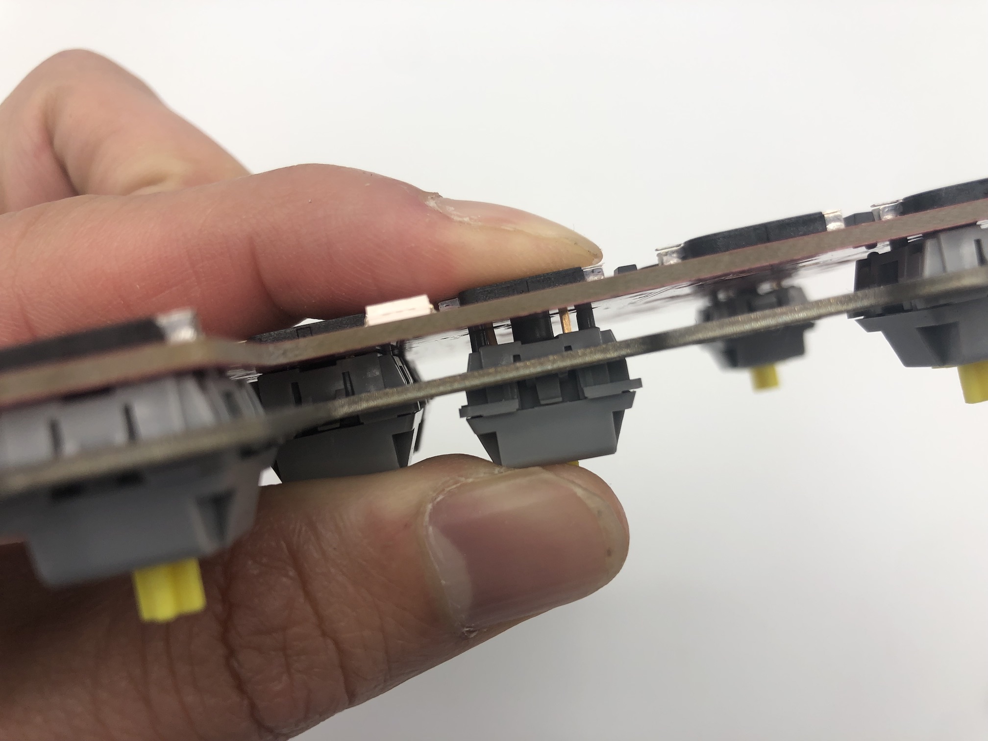 Hands squeezing switch plate and PCB together