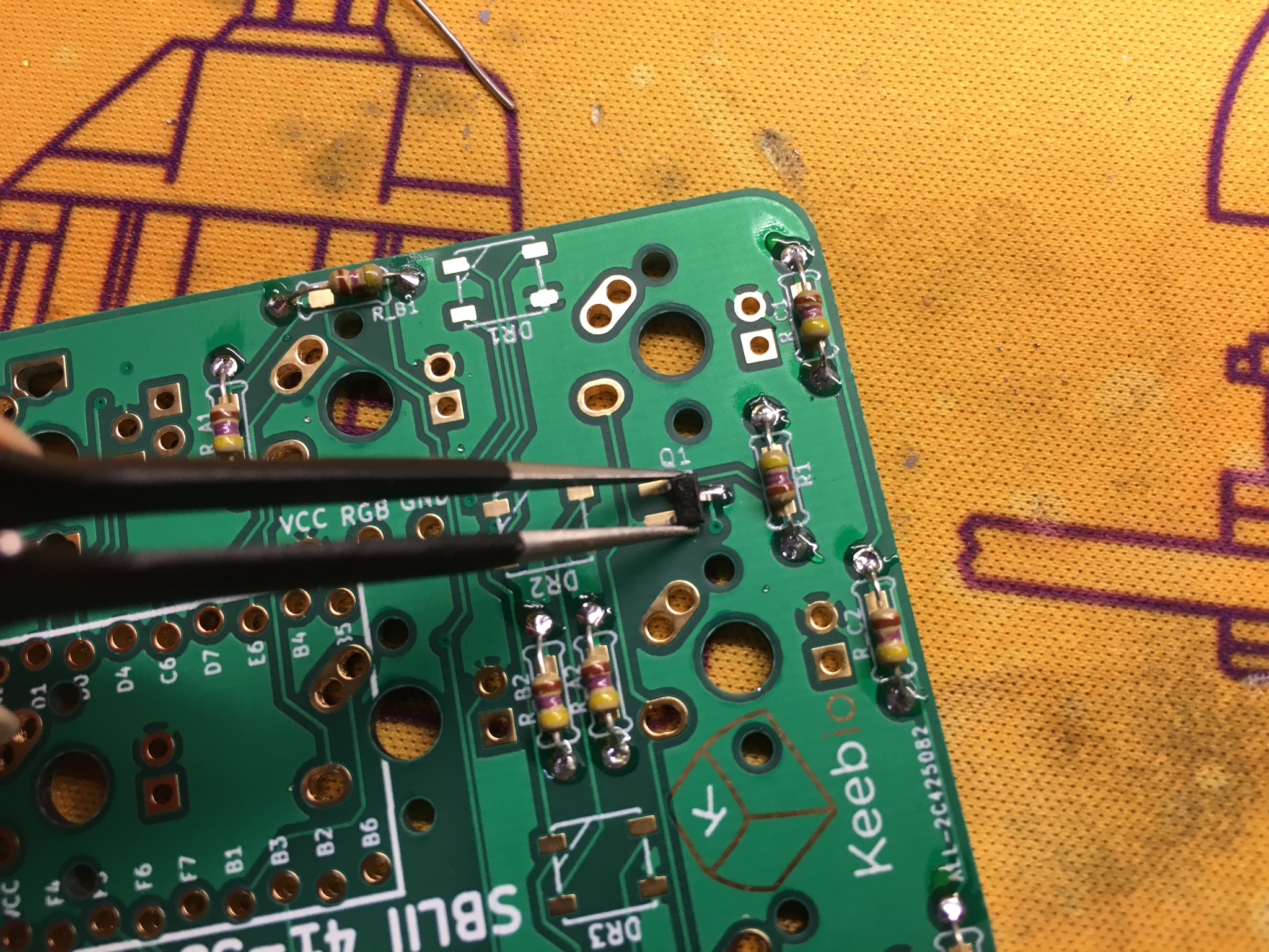 Tweezers holding MOSFET on PCB pad