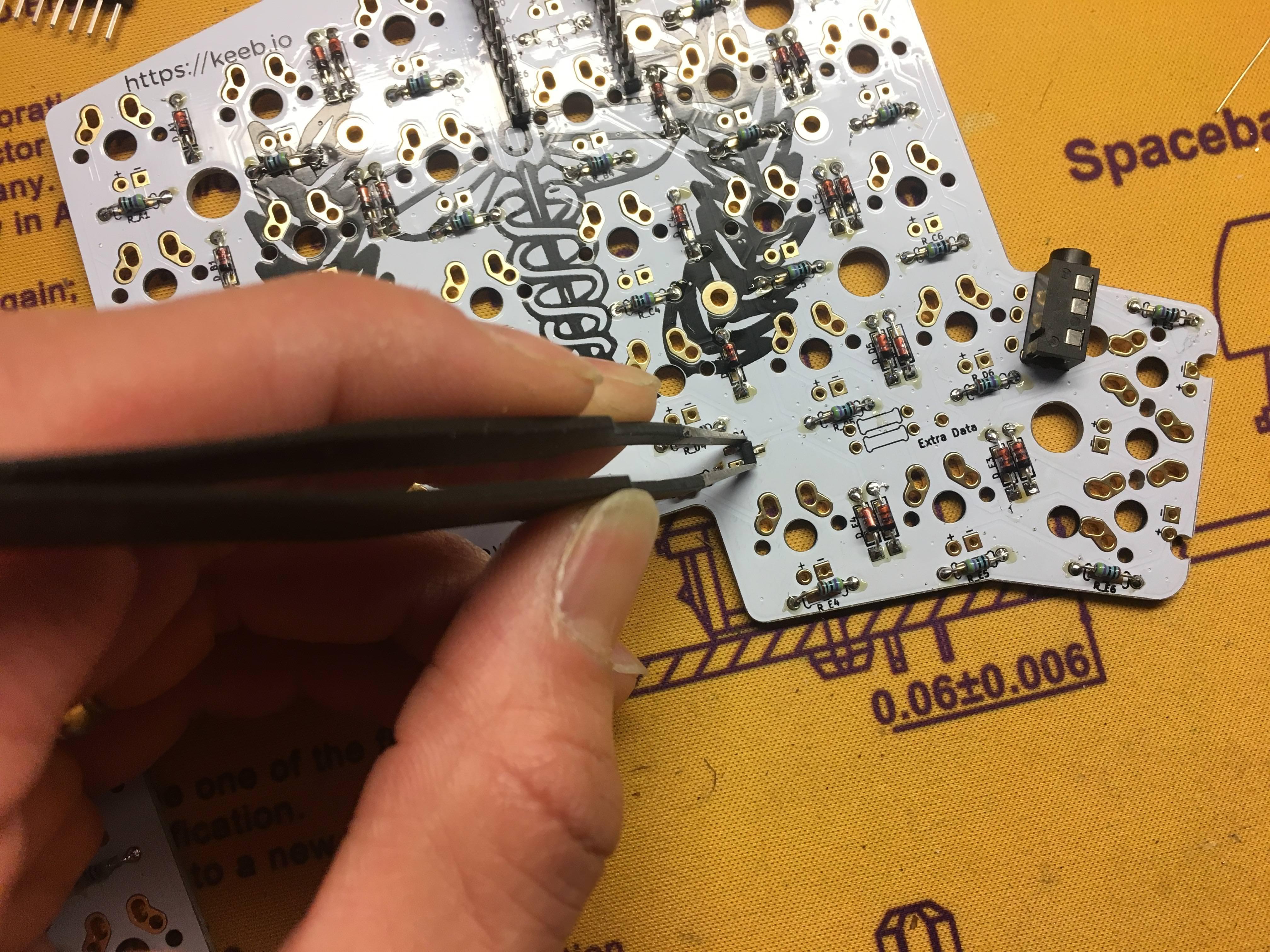 MOSFET held with tweezers, soldering first pin